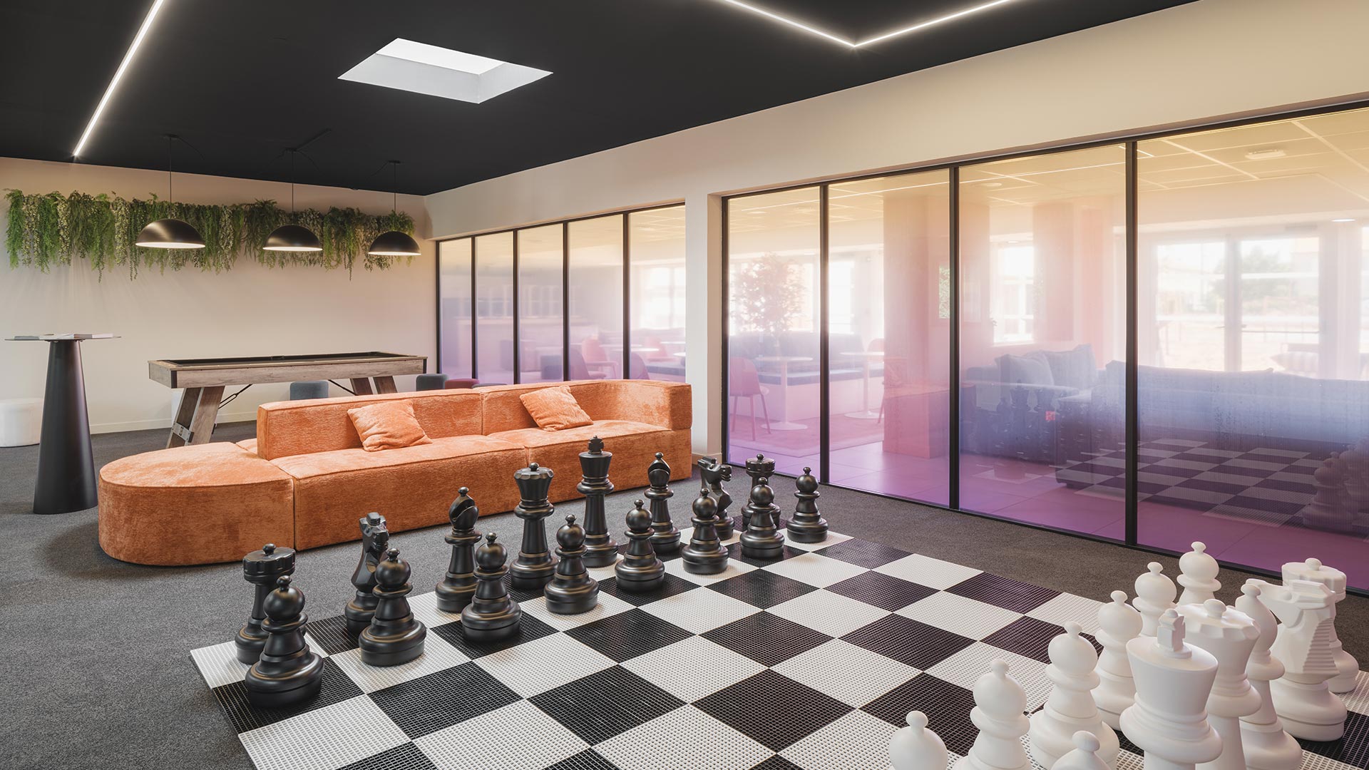 Espace ouvert et lumineux avec billard, jeu d'échecs géant et grand canapé confortable.