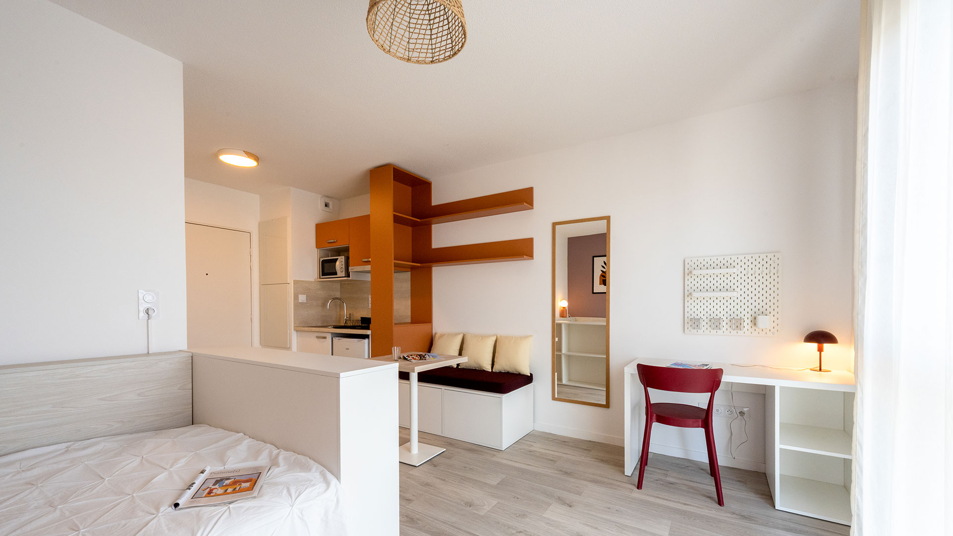 Studio meublé avec espace nuit, kitchenette équipée, coin repas, bureau et rangements.